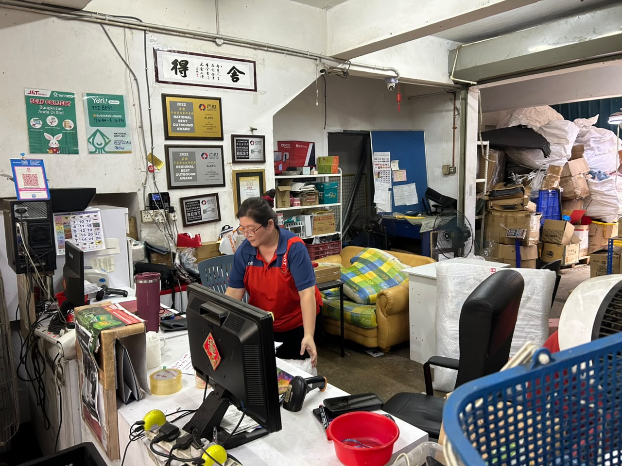 BEST Express Kepong staff at workstation with National Best Outbound award plaques visible on the wall